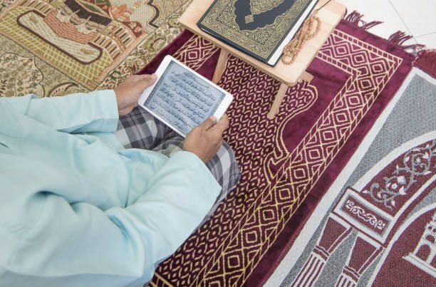 Muslim man reading Quranic courses using tablet at home during Ramadan