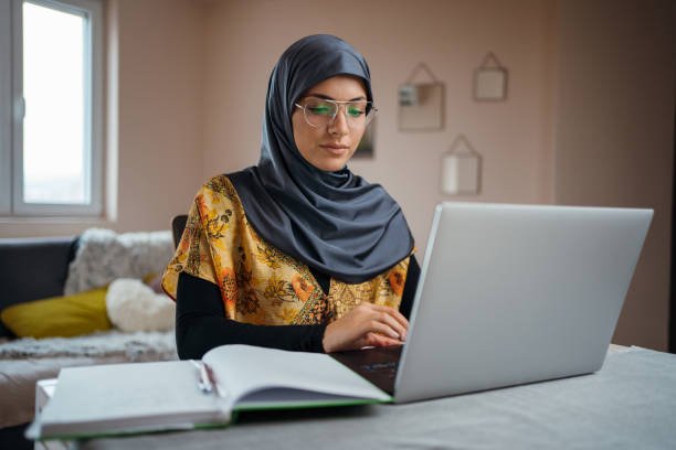 Young Muslim Woman teach arabic studies on laptop, sitting at the desk at home.