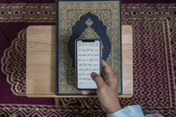 in Canada Asian Muslim man reading digital Al-Quran using smart phone at home during Ramadan