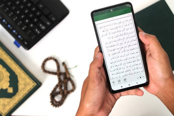 UK Muslim worker taking a break to recite the Holy Quran on his phone during Ramadan